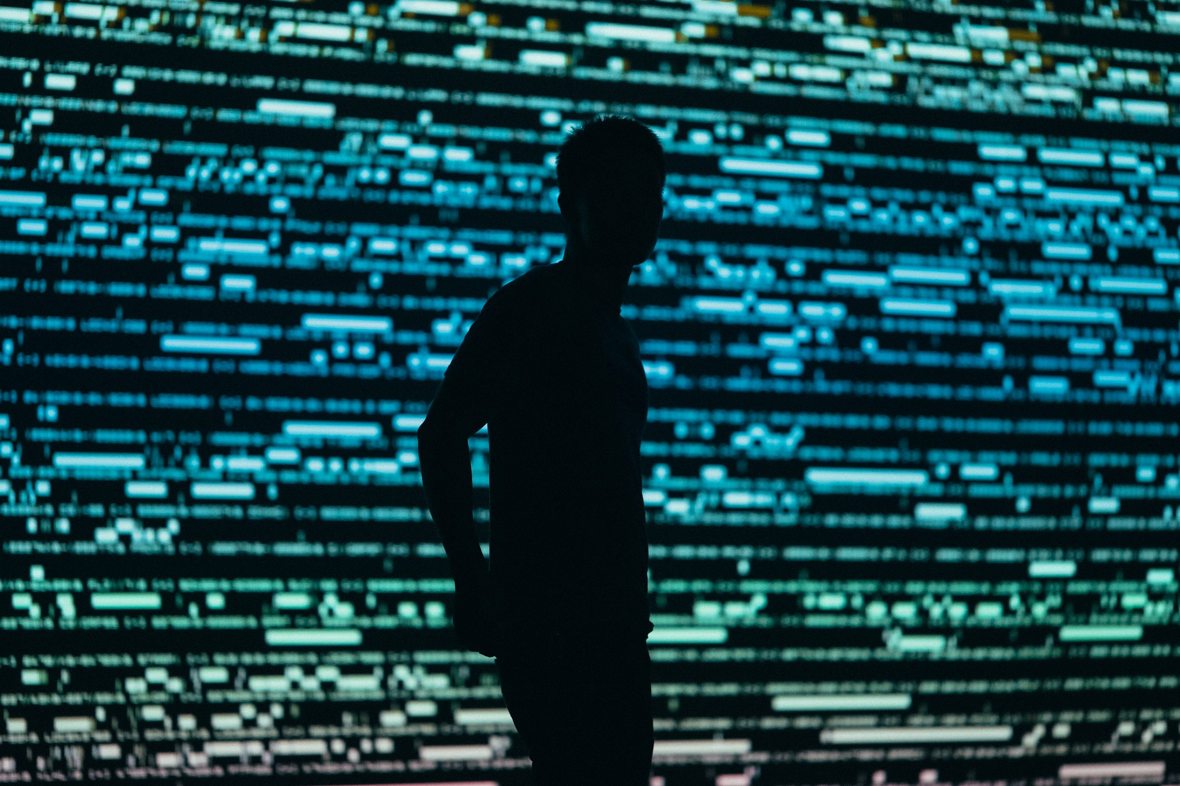 Silhouette of a person in front of a wall of streaming data